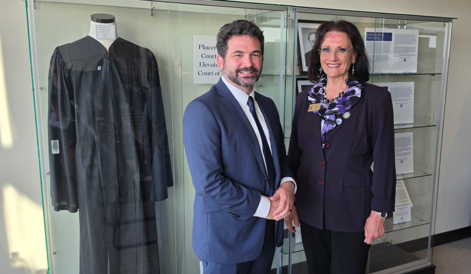 Supervisor Jones standing with a colleague in front of a display case with a judge's robe on display